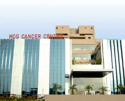 A tall building with a red sign on top of it saying HCG Cancer Centre.